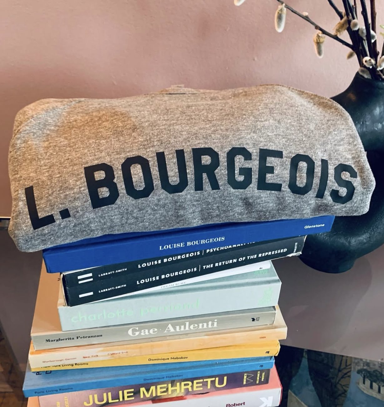 A Sororitées L. Bourgeois sweatshirt draped over a stack of art books